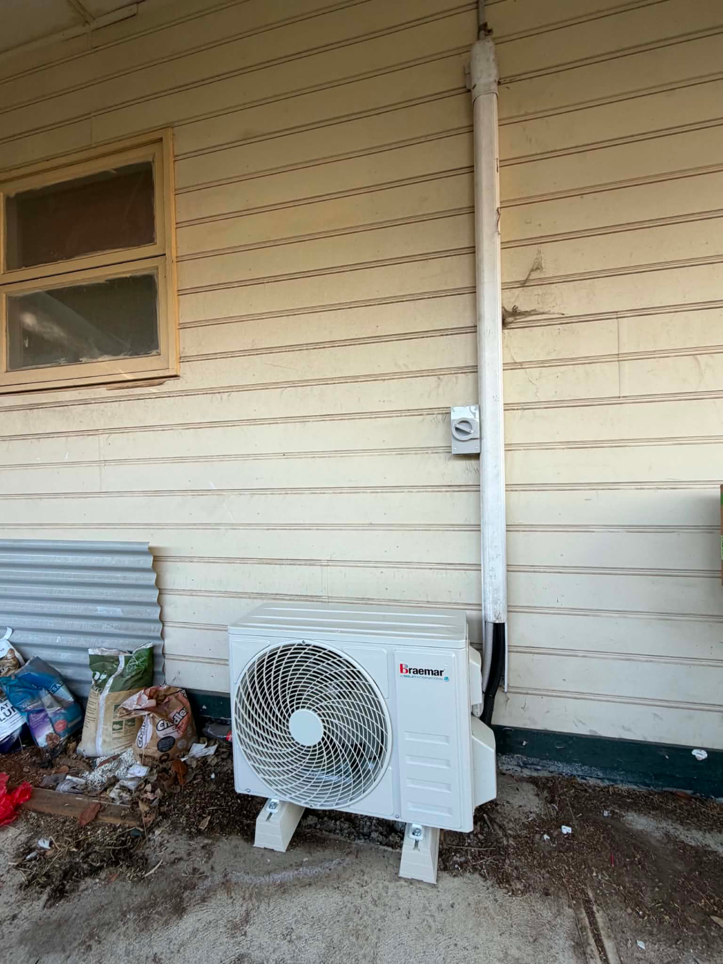 Braemar outdoor unit installed on feet beside a weatherboard wall